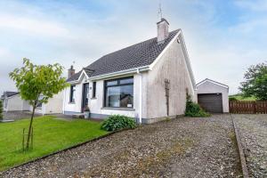 ein weißes Haus mit einem Fenster auf einer Kieseinfahrt in der Unterkunft 3-Bed Portballintrae Home | Wi-Fi, Garden, Parking in Portballintrae