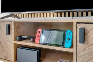 a cabinet with a tv and a game console at The Van Gogh Loft - By Raymond Properties in New Malden