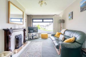 ein Wohnzimmer mit einer grünen Couch und einem Kamin in der Unterkunft 3-Bed Portballintrae Home | Wi-Fi, Garden, Parking in Portballintrae