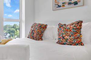 a white bed with two pillows on it with a window at The Van Gogh Loft - By Raymond Properties in New Malden