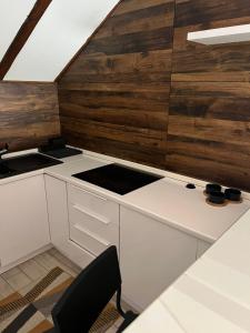 una cucina con armadietti bianchi e pareti in legno di Stan na Dan Centar a Niš