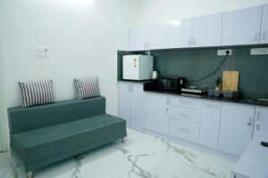 a kitchen with white cabinets and a green couch at La Maison Du Bonheur in Pondicherry
