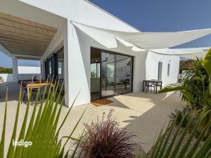 a white house with a patio with a table at Villa Paz -Moderno Privado Nuevo Piscina Vistas a Golf y Lago in Ayamonte