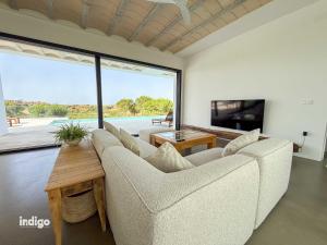 a living room with a couch and a large window at Villa Paz -Moderno Privado Nuevo Piscina Vistas a Golf y Lago in Ayamonte