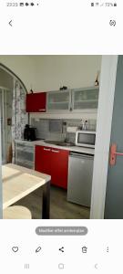 una cocina con armarios rojos y una mesa. en Les roses à la plage, en Veules-les-Roses