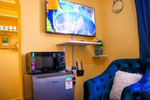 a room with a tv and a refrigerator and a chair at Khalisee homes studio apartment 3 in Voi
