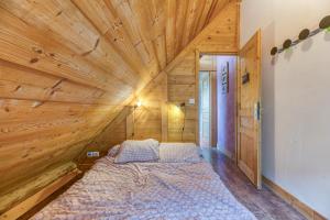 a bed in a room with a wooden ceiling at Auberge Passoud 203 in Vaujany