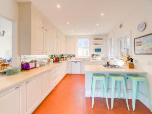 シービューにある5 Bed in Seaview 93445の広いキッチン(白いキャビネット、青いスツール付)