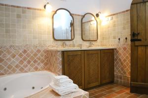 a bathroom with a tub and a sink and mirrors at Casa do Limoeiro - sleeps up to 4 comfortably in Serpa