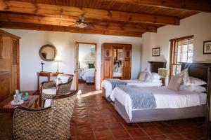 a bedroom with two beds and a table and chairs at De Denne Country Guest House in Oudtshoorn +159 photos