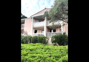 a pink building with a balcony and some bushes at Grabels Soleil Calme & Piscine in Grabels