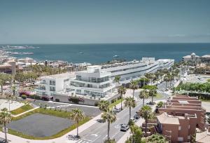 ein großes weißes Gebäude mit Palmen und dem Meer in der Unterkunft Hotel Baobab Suites in Adeje