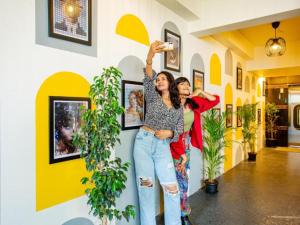 バンガロールにあるThe Hosteller Bangalore, Manyata Tech Parkの二人の女性が壁の横に立って両手を挙げている +12枚の写真