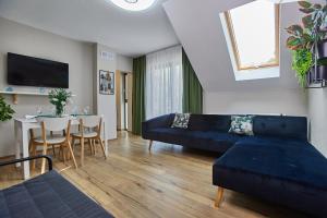 a living room with a blue couch and a table at Apartamenty Śniadanie do Łóżka in Pobierowo