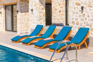a group of chairs next to a swimming pool at Spacious 2BR Stone Villa with Pool & BBQ in Kalkan