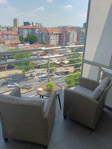 a balcony with two chairs and a table and a view of a city at Alacaster B apartman in Novi Sad