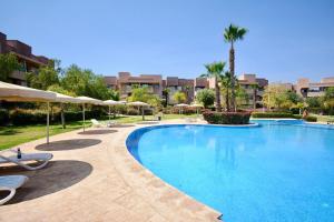 una gran piscina con sillas y sombrillas en Jade Haven 2 Bed Apt golf view, en Marrakech