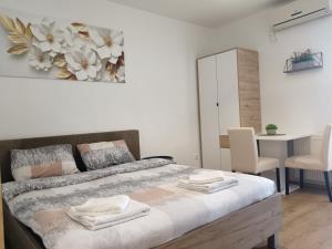 a bedroom with a bed with towels on it at Alacaster B apartman in Novi Sad