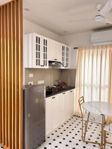a kitchen with white cabinets and a table and a refrigerator at Heritage The Bosque By StayUkiyo in Mapusa