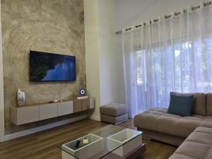 a living room with a couch and a tv on a wall at ApHEARTments in the Bay of Lalzi, Lura 1 in Mullini i Danit