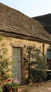 a stone house with a white door and flowers at Stunning stone cottage on Bath's doorstep in Box