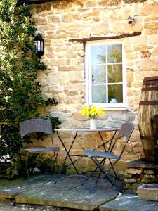 a table and two chairs in front of a stone wall at Stunning stone cottage on Bath's doorstep in Box
