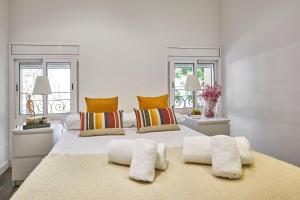 a white bed with two pillows and two windows at BBarcelona Sant Pau Flat in Barcelona