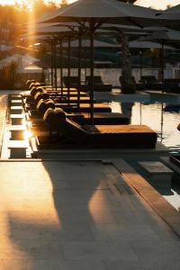 a row of lounge chairs and umbrellas in a pool at Trypiti Resort Blue Dream Palace and Hive Water Park in Limenaria