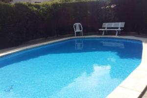 a blue swimming pool with a bench and a table at Casa adosada con piscina comunitaria Solo familias no grupos de jovenes in Salou
