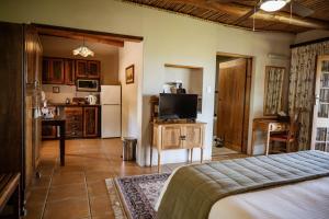 a living room with a bed and a kitchen at De Denne Country Guest House in Oudtshoorn