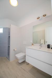 ein Badezimmer mit Waschbecken, Toilette und Spiegel in der Unterkunft Rua do Paraiso 15 Oceanview Carvoeiro Retreat in Carvoeiro