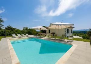 a swimming pool with chairs and umbrellas and a house at Villa La Gioconda in Arezzo