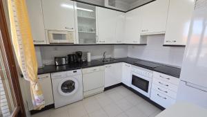 a kitchen with white cabinets and a washer and dryer at Dúplex frente la playa de Ostende in Castro-Urdiales