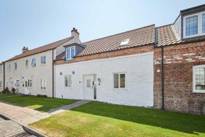 une grande maison en briques avec une cour d'herbe dans l'établissement Host & Stay - Easton Meadows Holiday Cottage, à Boynton