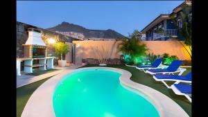 una piscina in un cortile con sedie e una casa di Villa Tenerife Luxe ad Adeje