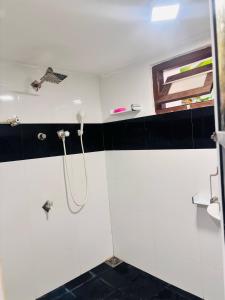 y baño con ducha y azulejos blancos y negros. en Spl inn, en Trincomalee