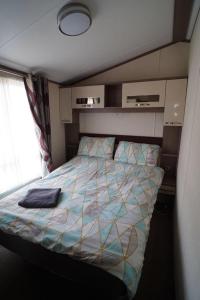 ein Schlafzimmer mit einem Bett in einem kleinen Zimmer in der Unterkunft Tranquil 3Bedroom Caravan Pets stay Free in Hunstanton + 14 Fotos