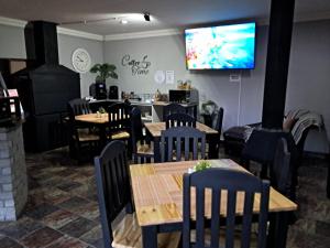 a dining room with tables and chairs and a tv at Villa Mariss Guesthouse in Kraaifontein