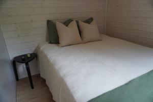 a small bedroom with a bed with pillows and a table at Stuga med strandbastu in Oravais