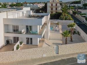 an aerial view of a white building with palm trees at Villa Mediterranea Apartments - Seaview, Pool & Garden in Bari