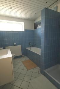 a blue tiled bathroom with a tub and a sink at TheGilgahouse Familyroom! in Nakskov +7 photos