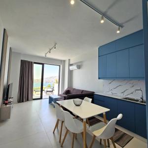 eine Küche mit blauen Schränken sowie einem Tisch und Stühlen in der Unterkunft Blue Horizon And Seaside Serenity in Sarandë