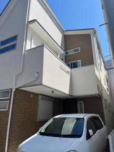 a white car parked in front of a building at 東京都新宿区渋谷区吹き抜けりリビング in Tokyo