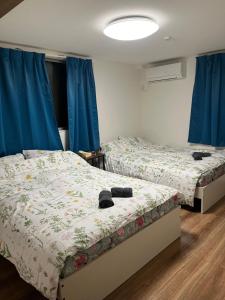 two beds in a room with blue curtains at 東京都新宿区渋谷区吹き抜けりリビング in Tokyo
