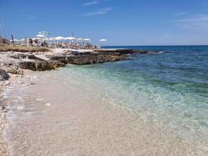 a beach with rocks and the ocean on a sunny day at Casa Rosalia in Cozze +14 photos