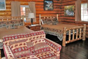 Dormitorio en cabaña de madera con 2 camas y sofá en Authentic Log Cabin with a Deck in Chugach National Forest, Alaska, en Cooper Landing
