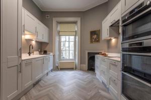 バースにあるPierrepont Houseの白いキャビネットと暖炉付きの広いキッチン