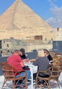 un gruppo di persone seduti a un tavolo di fronte alle piramidi di Mass Of giza pyramids a Il Cairo