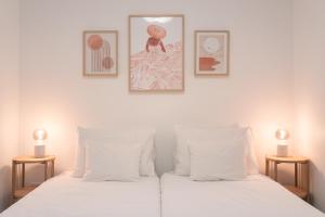 a bedroom with two white beds with two lamps at Barlavento by An Island Apart in Porto Santo