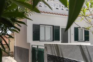 a white house with green shutters and a fence at Barlavento by An Island Apart in Porto Santo +39 photos